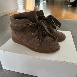 Bruna mockasneakers Isabel Marant - Snygga bruna sneakers från Isabel Marant i mocka med perforerade detaljer och breda snören. Skorna har en platt gummisula och rund tå, perfekt för dig som gillar en avslappnad men trendig stil. Passar 36-38❤️ Pris kan diskuteras! 