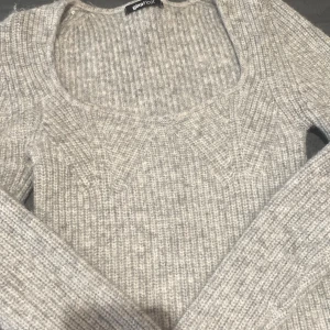 Grå ribbstickad tröja Gina Tricot - Supermjuk grå ribbstickad tröja från Gina Tricot med bred, rundad urringning och långa ärmar. Tröjan har en lite croppad passform och är perfekt för lager-på-lager under kyliga dagar. Materialet är stickat och känns riktigt cozy.