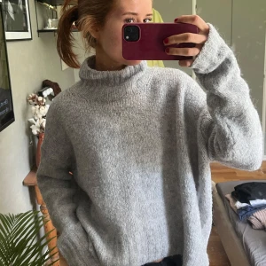 Grå stickad polotröja oversized - Mysig och oversized grå stickad polotröja med lång ärm och hög krage. Perfekt för kalla dagar och enkel att styla med jeans eller kjol. Tröjan har en avslappnad passform och är superbekväm att bära. Skitsnygg verkligen men har jättemånga likadana…❤️