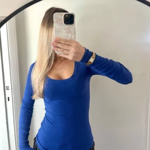 Blå ribbad långärmad tröja - Snygg blå långärmad tröja med ribbad struktur och rundad, djup urringning. Perfekt för dig som gillar en enkel men stilren look. Tröjan sitter tajt och är superenkel att matcha med jeans eller kjol. Aldrig använd. 🌸