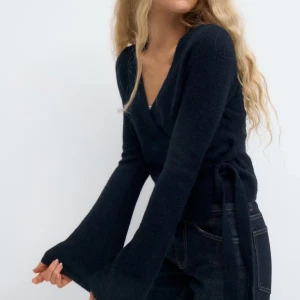 kofta  - Mysig mörkblå omlottkofta från Gina Tricot med knyt i sidan och v-ringad hals. Koftan har långa, lite utsvängda ärmar och är gjord i ett mjukt stickat material. Perfekt att slänga på sig när det är kyligt ute.