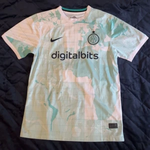 Inter Milan bortatröja 2022/23 Nike S - Inter Milans bortatröja 2022/23 från Nike i Dri-FIT-material. Tröjan är vit med ljusblått kartmönster, svart Nike-logga och klubbmärke på bröstet. Sponsorer digitalbits och Lenovo tryckta på fram- och baksidan. Klassisk rund hals och korta ärmar.