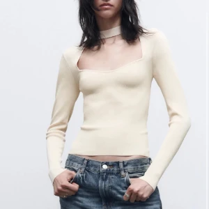 Beige långärmad topp med choker - Trendig beige långärmad topp med fyrkantig urringning och inbyggd choker-detalj runt halsen. Sitter tight och har en clean, minimalistisk look som passar perfekt till jeans eller kjol.