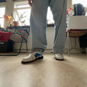 Vita och blåa vintage sneakers - Säljer ett par vita och blå skor med skön passform. Skorna har klassisk och stilren design. Perfekta för dig som gillar en relaxed och chill stil. 