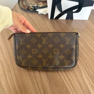 Louis Vuitton pochette - Säljer nu min fina Louis Vuitton pochette väska. Axelbandet har tyvärr gått av, vilket man kan se på läderbiten, annars är den i fint skick! Har använt den som en clutch💌 den är äkta, och bild på äkthetsbevis skickas till köparen