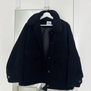 Svart teddyjacka från Zara - Mysig svart teddyjacka från Zara med fickor framtill och knappar längs hela framsidan. Använd en del men är i bra skick😍