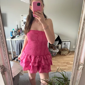 Rosa axelbandslös volangklänning - Säljer denna jättefina klänningen eftersom den är lite för kort på mig. Köpte utomlands och har aldrig använt