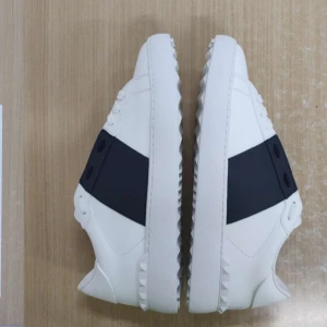 Vita sneakers med mörkblå detalj från Valentino - Snygga vita sneakers från Valentino med en bred mörkblå remsa på sidan och ikoniska nitar längs sulan. Skorna har rund tå och platt sula, perfekt för en stilren och modern look. Säljer då de inte satt nå bra, otroligt fräscha, dustbag och låda tillkommer. Har tyvärr inget kvitto, hör gärna av dig om du har frågor 🙌🏻