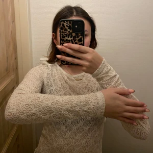 Vit spetsig långärmad topp  - Säljer en vit långärmad topp i spets. Tight passform och rund halsringning. Perfekt att styla med jeans eller kjol för en trendig look. 