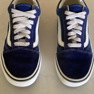 Blåa Vans - Säljer ett par helt nya vans sneakers i blått med vit sula och vit sidostrip. Skorna har vit snörning och den ikoniska gummisulan undertill. Perfekta för en avslappnad och stilren look.