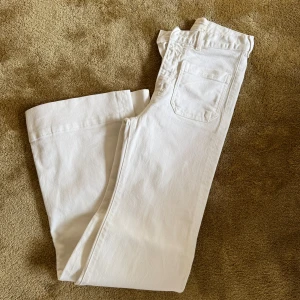 Vita jeans från Jeanerica - Säljer ett par vitajeans från Jeanerica. Byxorna har hög midja, raka ben och stora fickor fram. Använda en gång. Storlek 24/34