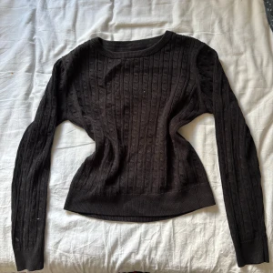 Svart kabelstickad tröja - Säljer en svart kabelstickad tröja med rund halsringning och långa ärmar.