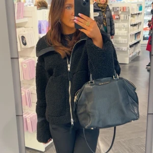 Svart trendig teddyjacka från hm - Säljer den populära svarta teddyjacka med dragkedja framtill. Jackan har en oversized passform och är långärmad. Perfekt för dig som vill ha en mysig och trendig jacka i garderoben.