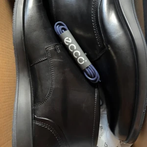 Svarta skinnboots från ECCO - Säljer ett par stilrena svarta boots från ECCO i äkta skinn. Skorna har snörning och en rund tå, perfekt för dig som vill ha en klassisk och clean look. Passar till många olika outfits och är riktigt bekväma.