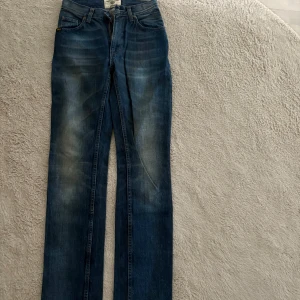 Blå jeans från Tiger of Sweden - Säljer ett par klassiska blå jeans från Tiger of Sweden i modellen 'new look mold'. Jeansen har raka ben och normal passform, med snygga slitningar och femficksdesign. Perfekta till många olika stilar!