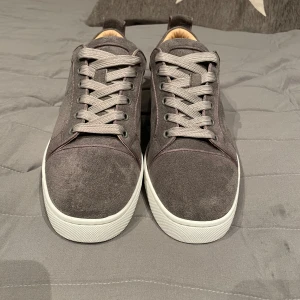 Gråa Christian Louboutin - Säljer ett par stilrena grå sneakers i mocka från Christian Louboutin med klassisk röd sula.Perfekta för dig som vill ha en clean look med exklusiv känsla. Dock inte helt nya använda nån gång men inget som direkt syns bara lite smuts på undersidan. Detta gör att priset på skorna får sänkas rätt mycket eftersom att de är dubbel begagnade. Jag köpte skorna för 8500kr🤯 som är sjukt mycket men nu har de tyvärr blivit för små så mitt pris är 1999kr🔥/ pris kan diskuteras!!!!⚠️