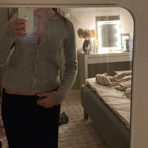 Ljusgrå kofta med knappar - Säljer en ljusgrå kofta med knappar framtill. Tröjan har lång ärm och är i ett mjukt, stickat material. 