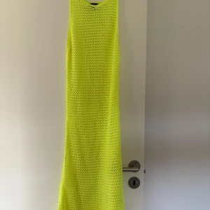 Neongul stickad långklänning från PrettyLittleThing - Säljer en neongul stickad långklänning från PrettyLittleThing. Klänningen är ärmlös och har en luftig, nätstickad design i 100% akryl. Perfekt för dig som vill sticka ut med en färgstark look! Aldrig använd