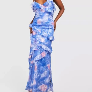 Blå långklänning med volanger och blommigt mönster - Superfin blå långklänning med volanger och blommigt mönster i rosa och vitt. Klänningen har omlott-detaljer och axelbandslös design, perfekt för sommarens alla tillfällen. Snygg och romantisk look!