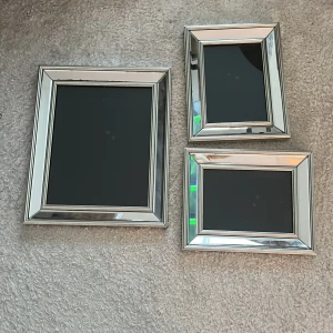 Tre silvriga SIA fotoramar - Säljer tre stilrena fotoramar i silverfärgad metall med bred kant. Två av ramarna är mindre och en är större, alla har en klassisk rektangulär form. Perfekta för att rama in foton eller posters och ge ett modernt intryck i hemmet.