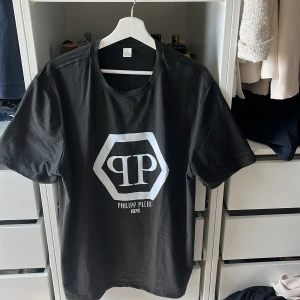 Svart t-shirt från Philipp Plein - Snygg svart t-shirt från Philipp Plein med stort vitt logotryck på bröstet. Klassisk passform och rund halsringning. Perfekt för dig som gillar stilrena och trendiga plagg. Storlek xl men passar även L den som vill ha en oversize look. 