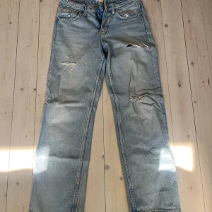 Ljusblå slitna jeans med raka ben lågmidjade  - Ljusblå lågmidjade jeans med raka ben och slitna detaljer på låren och knäna. Klassisk femficksmodell med normal passform och hög midja. Perfekta för en avslappnad och trendig look. Strl 152