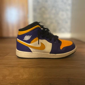 Jordan 1 lakers - Säljer ett par Nike Air Jordans med färgblock i lila, gult och vitt. Skorna har svart snörning, vit sula och klassisk Jordan-logga på sidan. Perfekta för dig som vill sticka ut med färg på fötterna. Storlek 38,5 jätte bra skick.