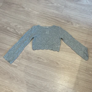 Ljusblå stickad croppad topp H&M - Superfin ljusblå croppad topp från H&M med lång ärm. Stickad i bomull med snyggt hålmönster och vågig kant nertill. Perfekt att styla med höga jeans eller kjol för en trendig look.