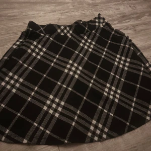 Svartvit rutig kortkjol FB Sister - Supersnygg svartvit rutig kortkjol från FB Sister i storlek S. Kjolen har klassiskt rutmönster och en lätt utsvängd form som ger en trendig vibe. Perfekt att styla med en stickad tröja eller en cool t-shirt för en chill look.