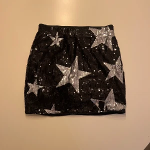 Svart kjol med silvriga stjärnor - aldrig använd, perfekt till fest! Har en tröja till den också på min profil!