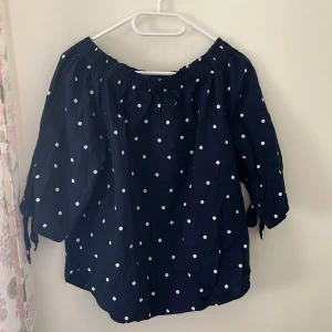 Mörkblå prickig blus från Hm - Superfin mörkblå blus med vita prickar från Hm. Offshoulder-modell med resår runt halsen och trekvartsärmar som knyts i ärmsluten. Luftig och lätt i bomull, perfekt för en chill och trendig look.
