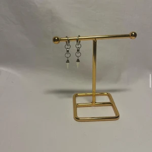 Silvriga örhängen med konformad detalj - Ett par coola silvriga örhängen med små konformade hängen. De har en minimalistisk design med ringar och spetsiga detaljer som ger en edgy vibe. Perfekta för dig som gillar unika accessoarer.