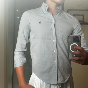Ljus blå Ralph lauren skjorta - • Nu säljs en ljus blå Ralph lauren skjorta i mycket bra skick 👔 • Storleken är 14 år och han på bilden är ca 177cm 📏 • Mycket snygg och fräsch skjorta nu till sommaren. Den är dessutom skön då den har ett avslappnat material ⭐️ • Nypris på denna är ca 1600kr men säljs för ett ofattbart bra pris på snåla 299kr ! • Det kan förekomma små fläckar men inget som märks av vid användning 🫟 • Hör av dig vid minsta lilla fundering 🤔💭 • Kolla gärna in profilen för andra schyssta plagg som raffe skjortor, l