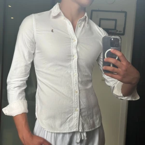 Vit skjorta från Ralph Lauren - • Nu säljs en vit Ralph lauren skjorta i mycket bra skick 👔 • Storleken är 16 år och han på bilden är ca 177cm 📏 • Mycket snygg och fräsch skjorta nu till sommaren ⭐️ • Skjortan har rosa ränder på manschetten samt insidan på kragen 🤍🩷 • Nypris på denna är ca 1600kr men säljs för ett ofattbart bra pris på snåla 249kr ! • Hör av dig vid minsta lilla fundering 🤔💭 • Kolla gärna in profilen för andra schyssta plagg som raffe skjortor, lanvins, replay jeans, Jacob cohen jeans och Dondups 🤝🤝