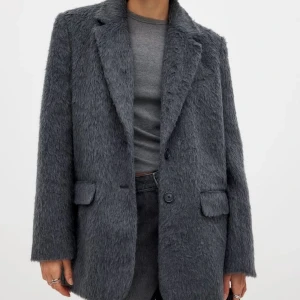 Oversized blazer - Säljer en snygg grå pälsblazer med kavajkrage och två knappar framtill. Jackan har en oversized passform och två fickor med lock. Perfekt för dig som vill ha en statementjacka med cool textur och stilren look. Använd 2 gånger . Nypris är 899kr