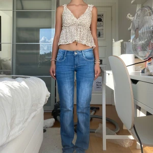 Blå jeans med strassdetaljer bak - Snygga blå jeans från Retro Bluest med raka ben och normal midja. Jeansen har coola strassdetaljer på bakfickorna och klassisk femficksdesign. Materialet är mjukt denim i bomull och passformen är normal. Perfekta för dig som gillar en avslappnad men ändå trendig look. Midjemått: 35cm och Innerbenslängden: 81cm