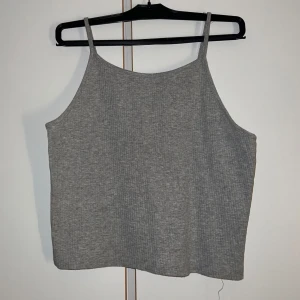 Grå ribbad linnetopp från Cubus - Säljer en enkel och stilren grå ribbad linnetopp från Cubusi storlek S. Toppen har smala axelband och ärmlös design, perfekt för lager-på-lager eller till jeans. Mjuk och stretchig känsla som gör den superbekväm att bära.