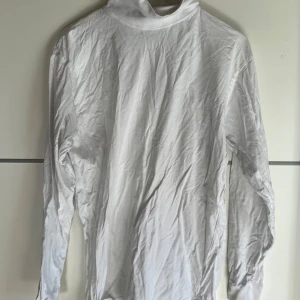 Vit polotröja från Cricket i bomull - Klassisk vit polotröja från Cricket i mjuk bomull. Tröjan har lång ärm och en hög krage som ger en clean och stilren look. Perfekt att styla lager på lager eller bära som den är. Enkel och tidlös design som funkar till allt.