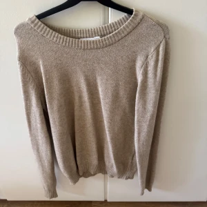 Beige stickad tröja från VILA - En stilren beige stickad tröja från VILA med rund halsringning och ribbade muddar. Perfekt för lager-på-lager och passar till både jeans och kjol. Mjuk och skön känsla, långärmad och i klassisk passform.
