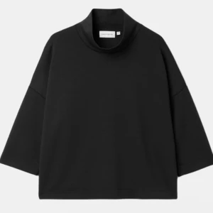 Svart polotröja från Carin Wester - Säljer en svart polotröja från Carin Wester i oversized modell. Tröjan har hög krage, vida trekvartsärmar och en rak, loose passform. Perfekt för dig som gillar minimalistisk och stilren design. Materialet är tunt och fladdrigt och bekvämt mot huden.