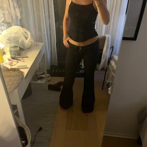 Svarta bootcut jeans låg midja - Säljer ett par svarta jeans med låg midja och bootcut-ben. Jeansen har klassisk femficksdesign, dragkedja och knapp framtill. Snygg passform som sitter tight upptill och släpper ut vid benslut. Perfekta till sneakers eller boots.