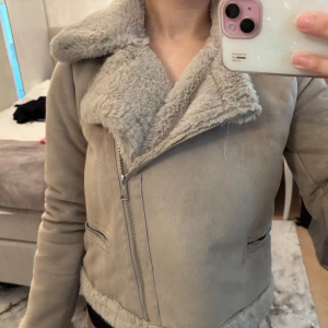 Beige teddyjacka med dragkedja - Snygg beige teddyjacka från pull and bear med fluffigt foder och krage. Jackan har en schysst asymmetrisk dragkedja, fickor med dragkedja och mjuka muddar. Perfekt för kalla dagar när du vill vara både varm och stilren. Använd sparsamt.