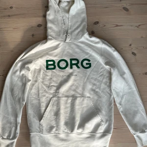 Vit hoodie från Björn Borg i storlek L - Snygg vit hoodie från Björn Borg med grön BORG-logga på bröstet. Använd fåtal gånger. Nypris 900kr. Pris kan diskuteras vid snabb affär.