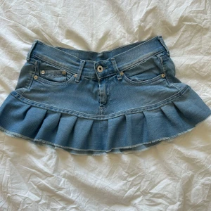 Blå jeanskjol med volanger från Pepe Jeans - Supersöt ljusblå jeanskjol från Pepe Jeans med volangkant nedtill och klassiska fickor fram och bak. Tunnare jeanstyg så sitter väldigt fint på. Midjemått ca 34 rakt över. Hör av dig vid funderingar!☀️🩷