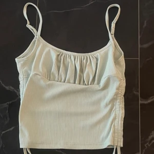 Ljusgrön topp - Ljusgrön ribbad topp med snörning som går att dra åt. I storlek M men den är liten i storleken!