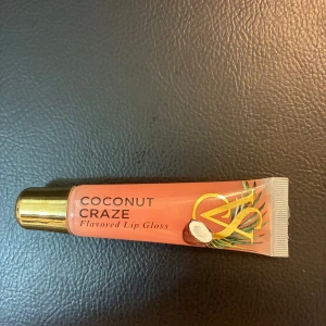 Victoria secret läppglans  - Coconut Craze flavored lip gloss från Victoria's Secret. Glanset har en ljusrosa nyans och kommer i en tub med guldig kork. Smaken är kokos och tuben rymmer 13g. Perfekt för dig som vill ha glansiga, återfuktade läppar med tropisk känsla. Har bara öppnat och kollat på det. Säljer denna för jag har många andra. 