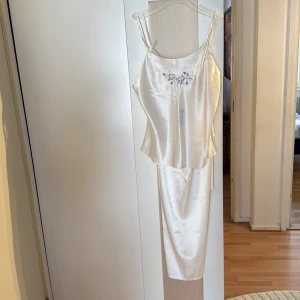 Pyjamasset  - Säljer ett superfint pyjamasset från KappAhl i elegant vit färg. Setet har tunna axelband och vackra broderade blommor framtill som ger en feminin och lyxig känsla. Mjukt material med följsam passform – perfekt för både mysiga kvällar och en stilren nattlook.
