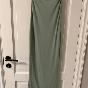 Ljusgrön långklänning med slits - Enkel och stilren ljusgrön långklänning med rak passform och slits nertill. Klänningen är ärmlös och har en mjuk, stretchig känsla som gör den superbekväm. Perfekt för dig som gillar minimalistisk stil och vill ha något lättburet.