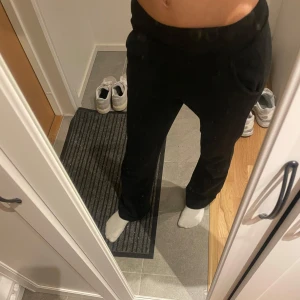 Svarta mjukisbyxor lågmidjade - Säljer ett par svarta mjukisbyxor med normal passform och resår i midjan. Byxorna har raka ben och är perfekta för chill dagar. Mjukt material som känns skönt mot huden och har fickor på sidorna.