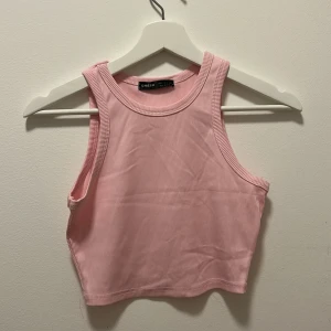 Rosa croppad linnetopp  - Säljer en ljusrosa croppad linnetopp. Toppen är ribbad och ärmlös med rund halsringning och tight passform. Perfekt för varma dagar. 